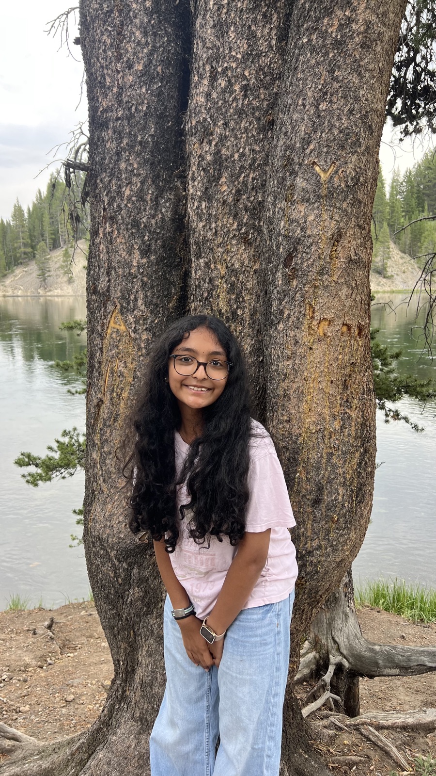 Vasudha standing by a tree at a lakeside