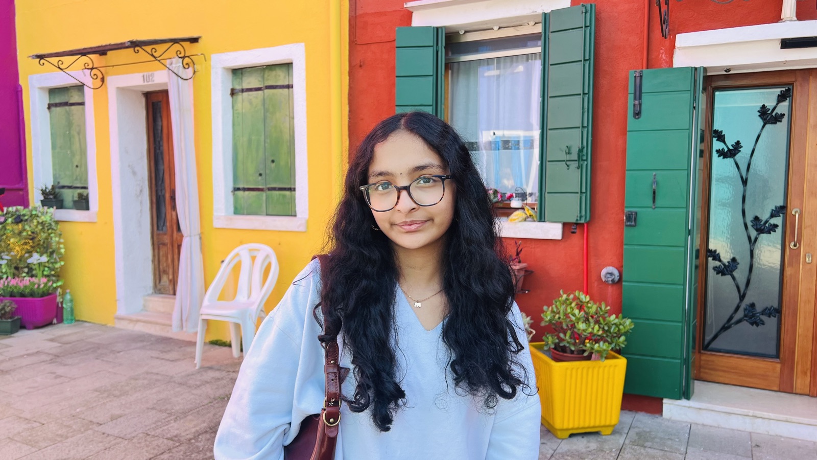 Vasudha smiling in front of brightly colored houses